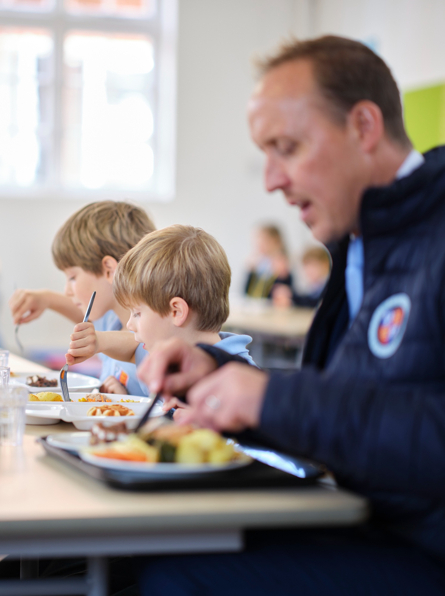 Pupils and teachers eating lunch when clicked it opens the Dame Bradbury's Early Years Menu